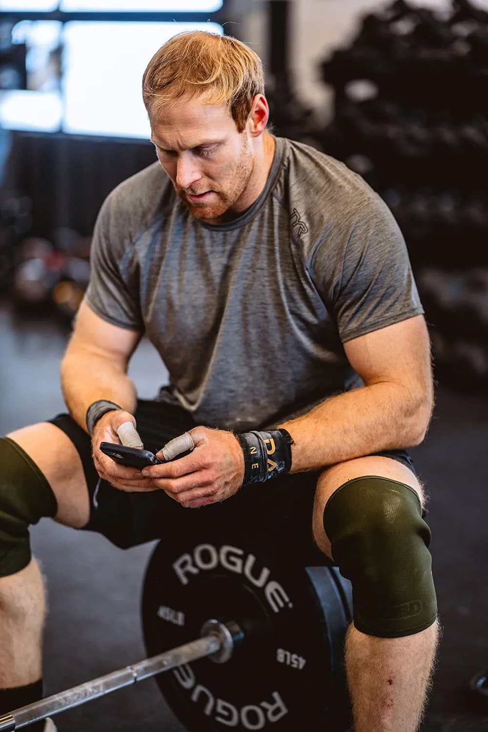 Athlete checking his phone while resting on a weight plate