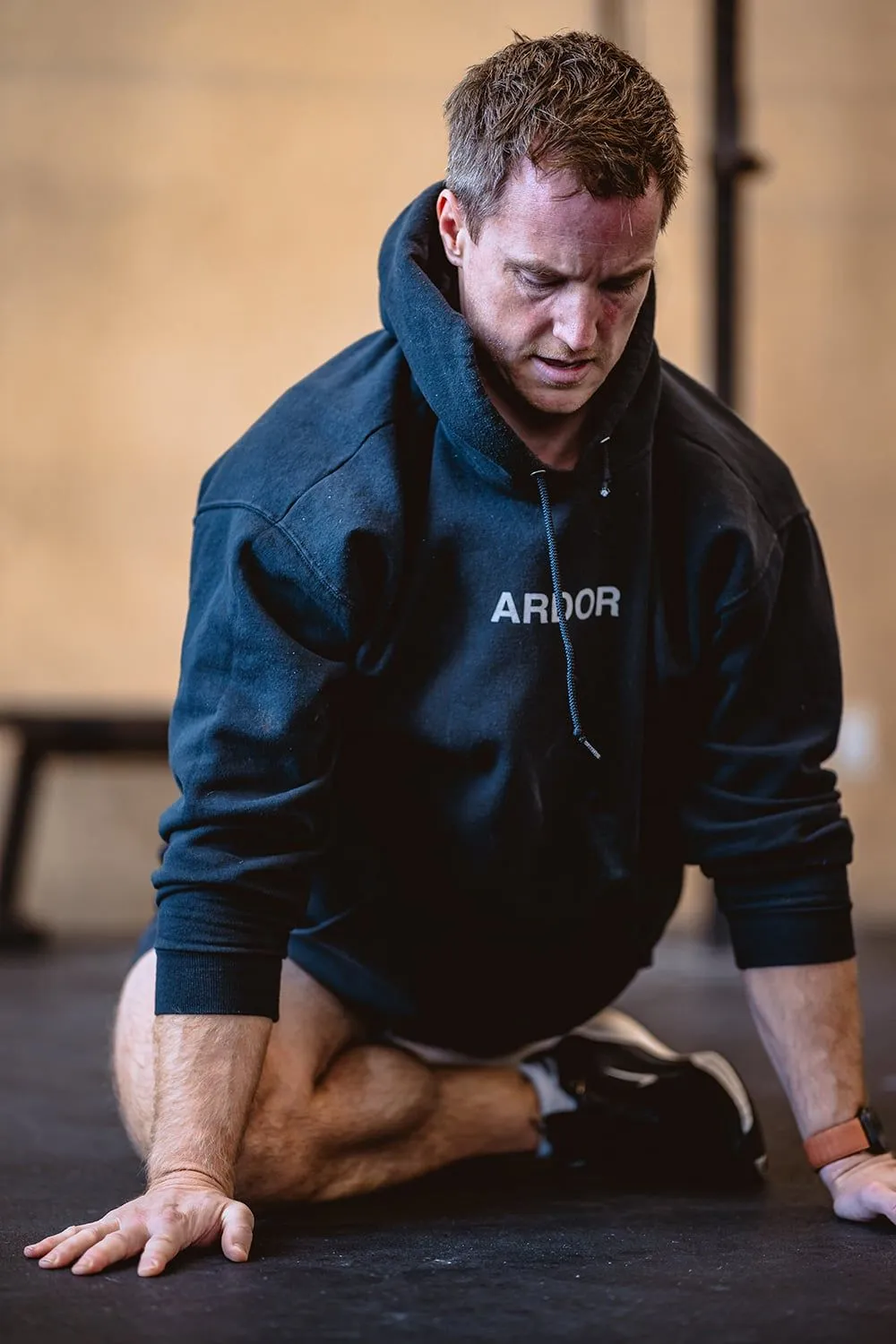 Athlete in an ARDOR hoodie resting on the gym floor